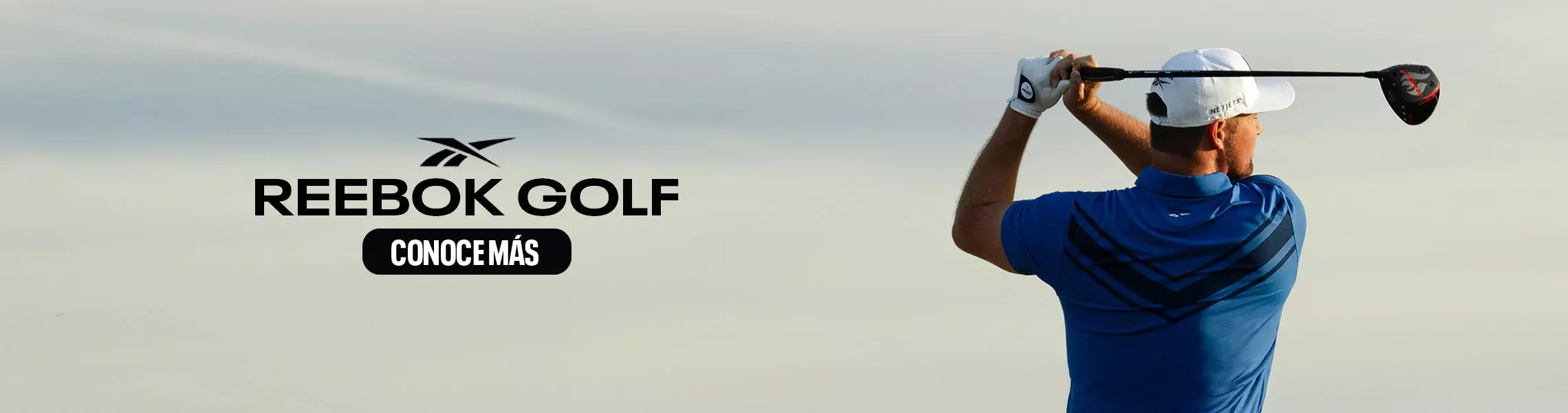 Modelo Reebok Golf de espaldas en polo azul con detalles oscuros, gorra azul, swing con hierro, fondo de &aacute;rboles y vegetaci&oacute;n.