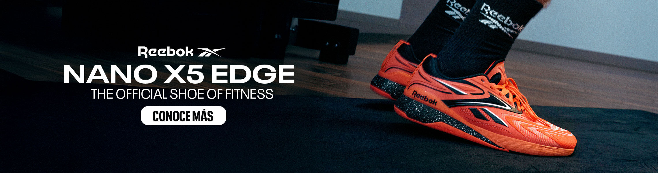 Banner mobile home Reebok Nano X5 Edge, tenis crossfit naranja ne&oacute;n con detalles negros y plateados junto a kettlebell met&aacute;lico sobre colchoneta negra, calcetines negros con logo Reebok, texto Nano X5 Edge The Official Shoe of Fitness y bot&oacute;n Conoce M&aacute;s.