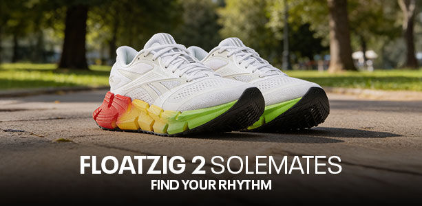 Banner desktop secci&oacute;n Reebok Floatzig 2 Solemates, par de tenis blancos con suela multicolor rojo amarillo verde sobre pavimento de parque, texto Floatzig 2 Solemates Find Your Rhythm, fondo natural con &aacute;rboles desenfocados.