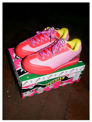 Par de tenis skate Reebok x IceCream Board Flip en tonos rosa rojo y amarillo ne&oacute;n colocados sobre la caja de edici&oacute;n especial verde rosa y blanco, sobre baldosas oscuras, iluminaci&oacute;n nocturna con flash, alta resoluci&oacute;n.
