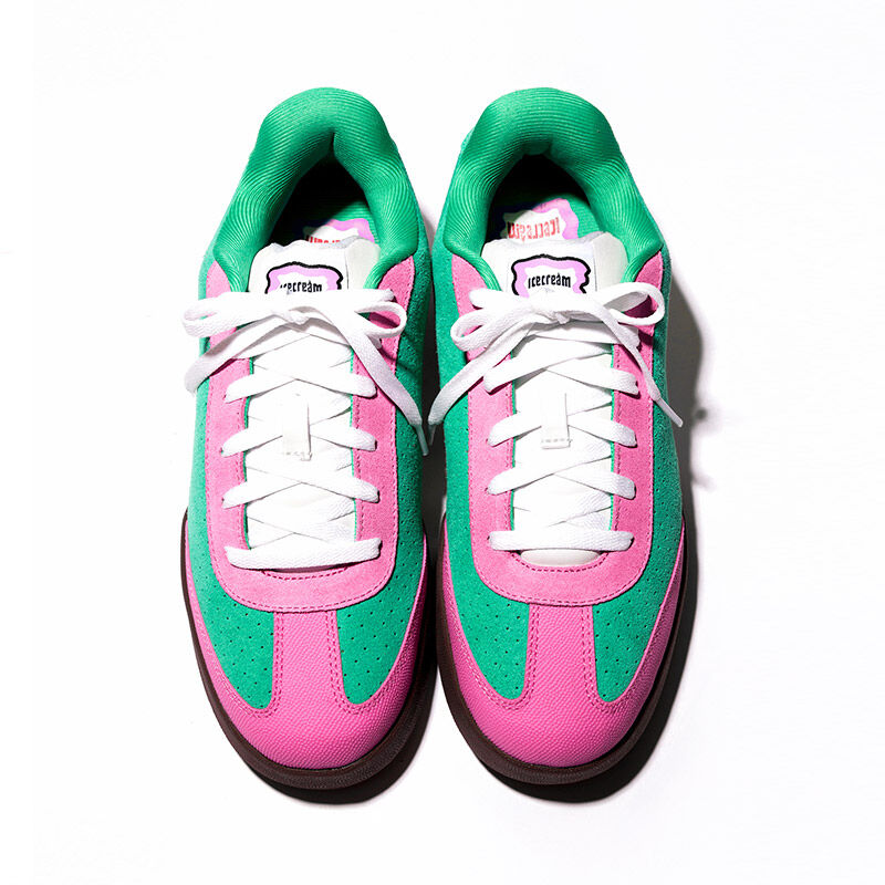 Vista cenital del par de tenis skate Reebok x IceCream Board Flip en combinaci&oacute;n verde rosa y blanco con cordones blancos, leng&uuml;eta con logo, suela caf&eacute;, sobre fondo blanco, dise&ntilde;o sim&eacute;trico.