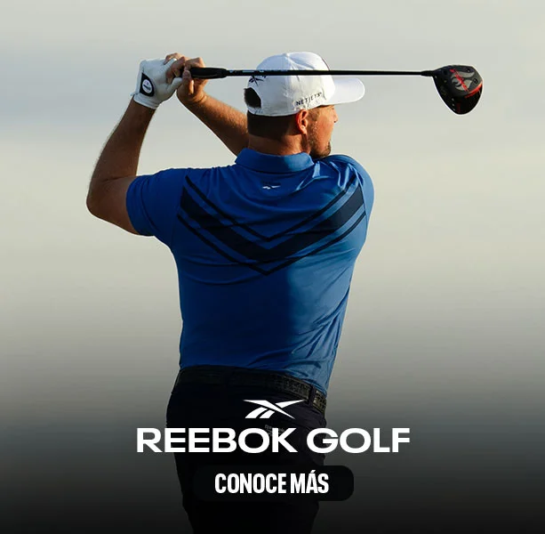 Modelo Reebok Golf de espaldas en polo azul con detalles oscuros, gorra azul, swing con hierro, fondo de &aacute;rboles y vegetaci&oacute;n.