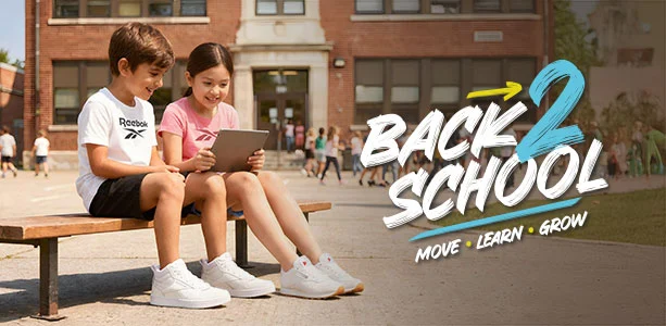 Banner desktop secci&oacute;n Reebok Back to School, ni&ntilde;o con playera blanca Reebok y ni&ntilde;a con playera rosa viendo una tablet frente al edificio escolar, ambos con tenis blancos Reebok, texto Back 2 School Move Learn Grow. Tenis Reebok blancos, tenis blancos para ni&ntilde;os, tenis deportivos blancos y tenis para la escuela