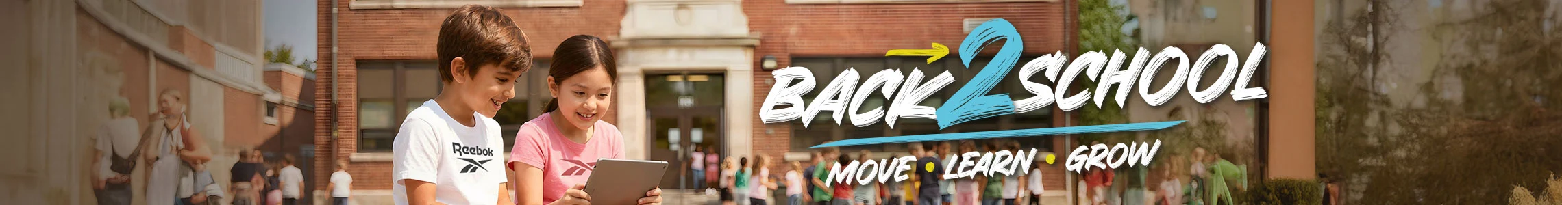 Banner desktop secci&oacute;n Reebok Back to School, ni&ntilde;o con playera blanca Reebok y ni&ntilde;a con playera rosa viendo una tablet frente al edificio escolar, ambos con tenis blancos Reebok, texto Back 2 School Move Learn Grow. Tenis Reebok blancos, tenis blancos para ni&ntilde;os, tenis deportivos blancos y tenis para la escuela