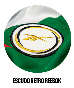 Detalle escudo retro Reebok bordado en dorado sobre jersey verde.