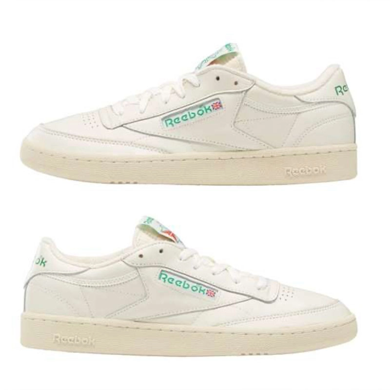 Recuadro de producto Reebok Club C 85 en color crema con dos vistas laterales sobre fondo blanco, logo Reebok verde en el costado y suela de goma, campa&ntilde;a Reebok x Karol G Born Classic. Reebok, Karol G, Club C 85, tenis blancos Reebok, Reebok Classics y Born Classic Worn For Life.