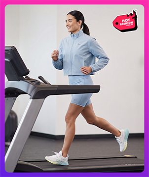 Look mobile Reebok Hot Fashion para mujer, modelo corriendo en caminadora con conjunto azul cielo Reebok de chamarra corta y short ciclista, tenis de running blancos Reebok, equipo de gimnasio de fondo, etiqueta Hot Fashion. Reebok mujer, ropa deportiva Reebok, conjunto deportivo, short ciclista, tenis blancos Reebok y rebajas Hot Fashion