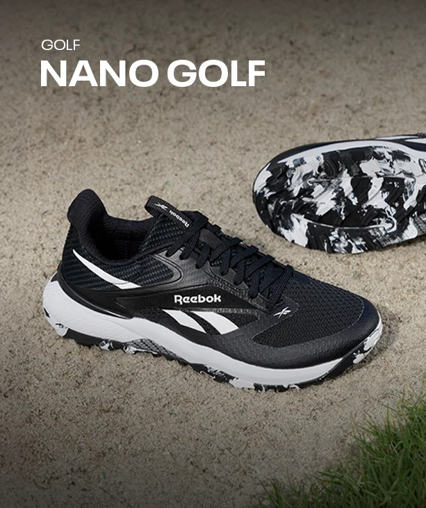 Silueta Reebok Nano Golf de golf, par de tenis negros con blanco, uno de lado mostrando la suela con estampado marmoleado, sobre tierra clara junto al pasto. Tenis de golf Nano Golf Reebok