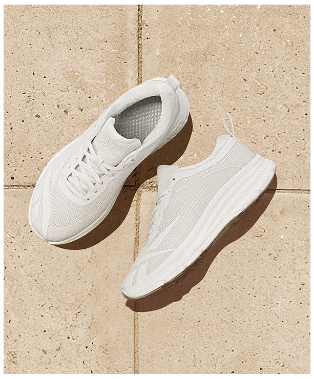 Portrait Reebok Back to School, par de tenis running blancos Reebok con upper de tejido transpirable y suela con acabado gum, vista superior sobre baldosas beige. Tenis Reebok blancos, tenis deportivos blancos, tenis running blancos y tenis para la escuela.