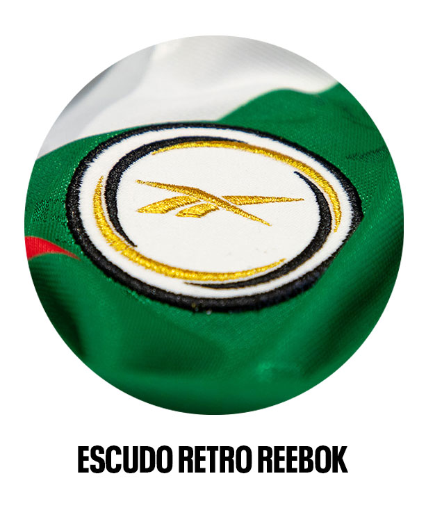 Detalle escudo retro Reebok bordado en dorado sobre jersey verde.