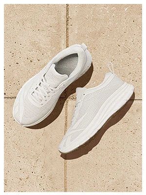 Portrait Reebok Back to School, par de tenis running blancos Reebok con upper de tejido transpirable y suela con acabado gum, vista superior sobre baldosas beige. Tenis Reebok blancos, tenis deportivos blancos, tenis running blancos y tenis para la escuela.