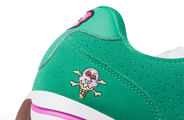 Detalle macro del bordado de calavera con forma de helado y huesos cruzados en tal&oacute;n del tenis Reebok x IceCream Board Flip, fondo verde con perforaciones, costuras grises, acabado texturizado premium.