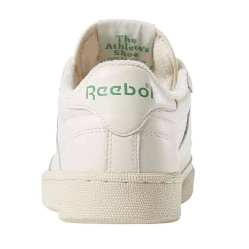 Recuadro de producto Reebok Club C 85 en color crema visto desde atr&aacute;s sobre fondo blanco, con logo Reebok verde en el tal&oacute;n y leyenda The Athlete's Shoe en el interior, campa&ntilde;a Reebok x Karol G Born Classic. Reebok, Karol G, Club C 85, tenis blancos Reebok, Reebok Classics y Born Classic Worn For Life