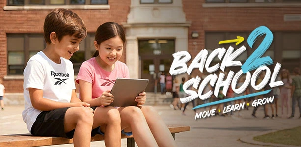 Head banner desktop Reebok Back to School, ni&ntilde;o con playera blanca Reebok y ni&ntilde;a con playera rosa viendo una tablet en banca frente al edificio escolar con estudiantes de fondo, texto Back 2 School Move Learn Grow. Tenis Reebok blancos, tenis blancos para ni&ntilde;os, tenis para la escuela y regreso a clases.