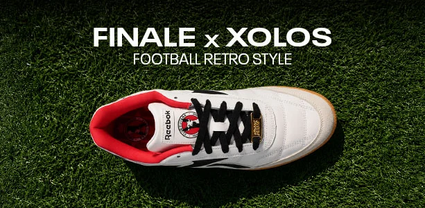 Cintillo desktop Reebok Finale x Xolos con texto Football Retro Style, vista superior de un tenis Reebok Finale blanco con agujetas negras, forro rojo y escudo del Club Tijuana Xolos sobre pasto verde. Reebok, Xolos, Club Tijuana, tenis Reebok Finale, tenis retro de f&uacute;tbol y colaboraci&oacute;n Reebok x Xolos