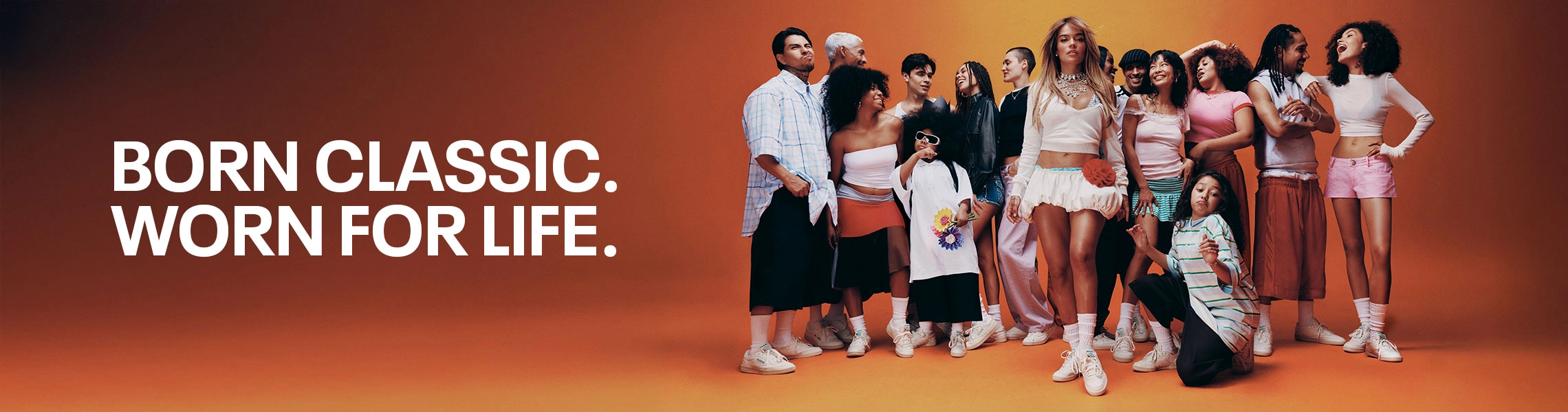 Head banner desktop de landing page Reebok x Karol G Born Classic Worn For Life, grupo diverso de personas de distintas edades y estilos posando en conjunto con Karol G al centro, todos con tenis Reebok Club C 85 blancos sobre fondo naranja. Reebok, Karol G, Club C 85, tenis blancos Reebok, Reebok Classics y campa&ntilde;a Born Classic Worn For Life.