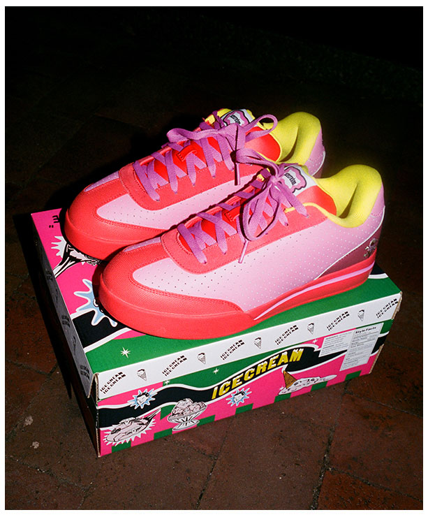 Par de tenis skate Reebok x IceCream Board Flip en tonos rosa rojo y amarillo ne&oacute;n colocados sobre la caja de edici&oacute;n especial verde rosa y blanco, sobre baldosas oscuras, iluminaci&oacute;n nocturna con flash, alta resoluci&oacute;n.
