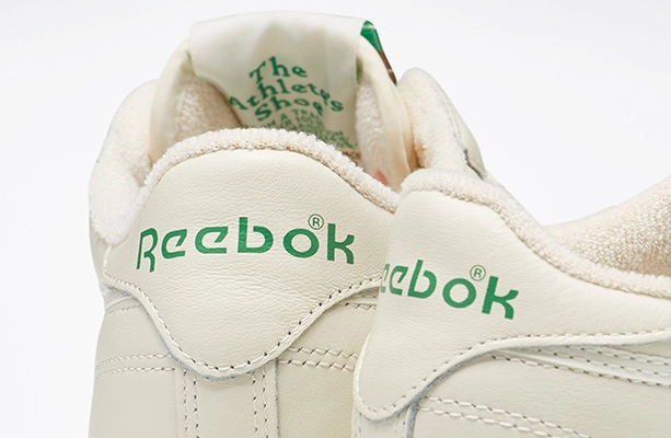 Detalle de los tenis Reebok Club C 85 en color crema mostrando el logo Reebok verde en el tal&oacute;n y la leyenda The Athlete's Shoe en el forro interior, campa&ntilde;a Reebok x Karol G Born Classic. Reebok, Karol G, Club C 85, tenis blancos Reebok, Reebok Classics y Born Classic Worn For Life.